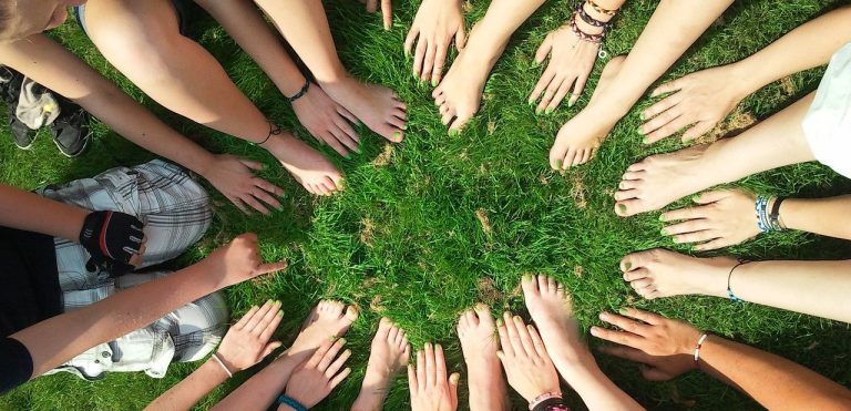 Verschiedene Hände, die in einem Kreis auf grünem Gras angeordnet sind.