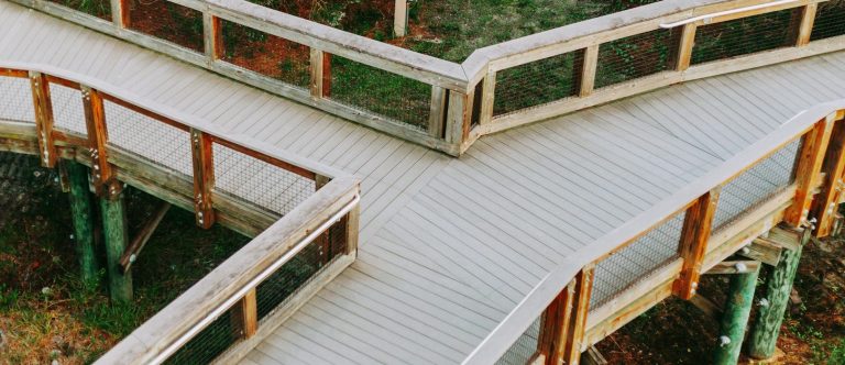 Holzgeplankter Weg mit mehreren Kurven und Abschnitten in einer grünen Umgebung.